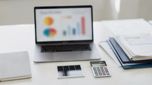 Vergleich von Solar-Anbietern am Schreibtisch mit Laptop, Unterlagen und Solarmodul-Muster