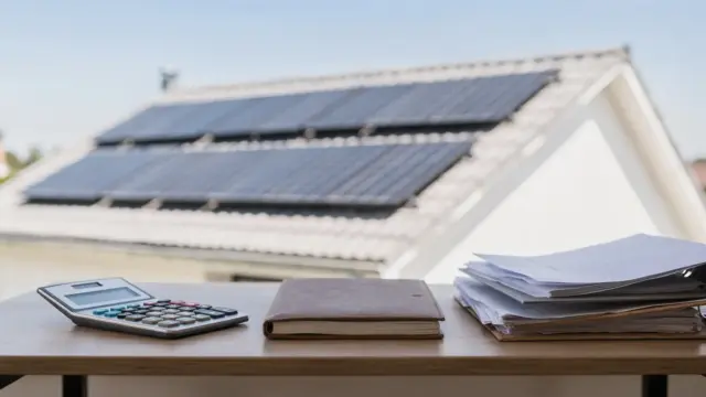 Photovoltaikanlage auf einem Hausdach mit Unterlagen zur Einkommensteuer bei PV-Einnahmen
