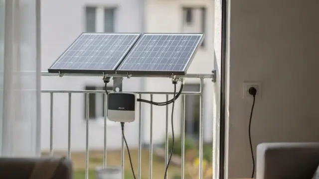 Balkonkraftwerk auf einem Balkon mit Solarmodulen, Wechselrichter und Anschluss an eine Steckdose